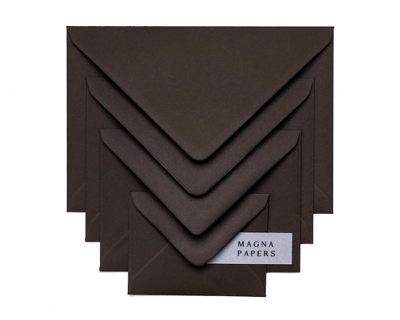 May include: A set of five brown envelopes of different sizes, stacked on top of each other. The envelopes are made from textured paper and have a subtle sheen. The smallest envelope has a white label with the text "MAGNA PAPERS" printed on it.