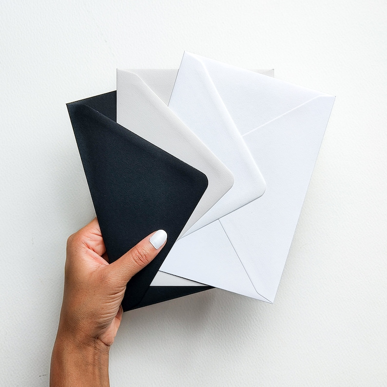 May include: A stack of envelopes in various shades of gray and black. The envelopes are folded and ready to be used for sending letters or cards.