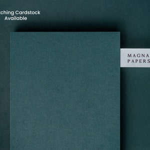 May include: A dark teal cardstock sample with the text "MAGNA PAPERS" printed on a white label.