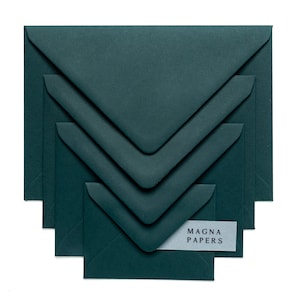 May include: A set of four dark green envelopes, nested inside each other, with the text "MAGNA PAPERS" on a white label on the smallest envelope.
