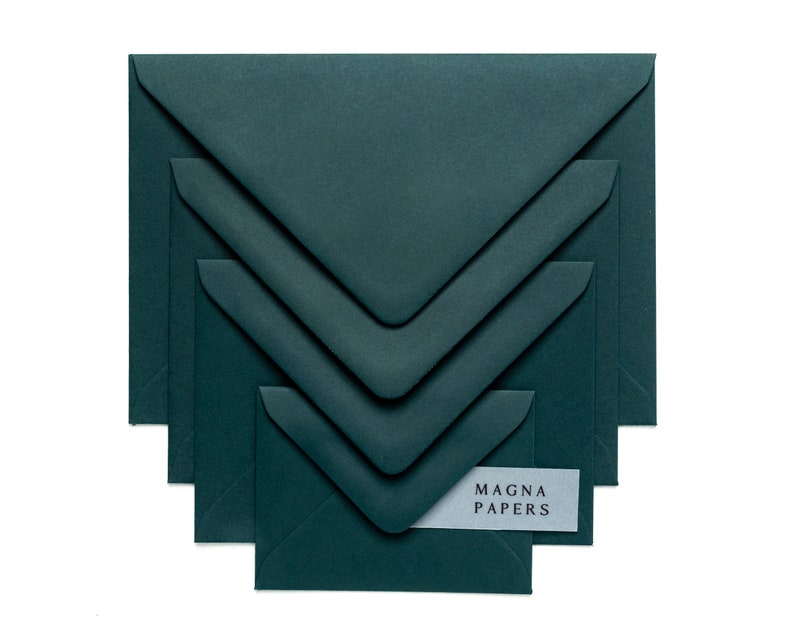 May include: A set of four dark green envelopes, nested inside each other, with the text "MAGNA PAPERS" on a white label on the smallest envelope.