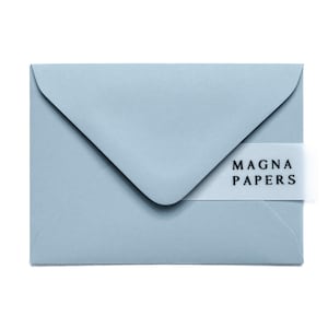 May include: A light blue envelope with a flap closure. A white band with the text "MAGNA PAPERS" is wrapped around the envelope. The envelope is a soft, muted blue color.