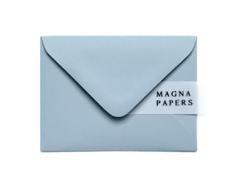 Könnte beinhalten: Hellblaue Umschlag mit dreieckiger Klappe. Ein weißes Band mit dem Text "MAGNA PAPERS" ist um den Umschlag gewickelt. Der Umschlag hat eine gedämpfte, pastellblaue Farbe.