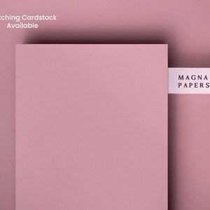 May include: A close-up of a pale pink cardstock sheet with a white label that reads "MAGNA PAPERS" on it.