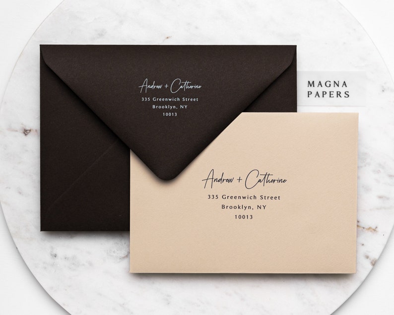 May include: Two envelopes with the names "Andrew + Catherine" and the address "335 Greenwich Street, Brooklyn, NY 10013" printed on them. The envelopes are on a marble surface. A small white label with the text "MAGNA PAPERS" is visible in the top right corner of the image.