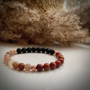 May include: A brown, black, and gold beaded bracelet with a mix of round and textured beads.