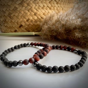 May include: Two beaded bracelets, one black lava stone and one red tiger's eye, with silver metal beads.