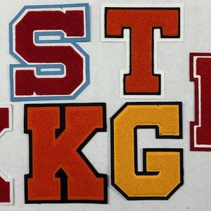 以下が含まれることがあります： 赤、オレンジ、白、黄色など、さまざまな色のバーシティレターパッチの詰め合わせ。文字にはC、S、T、K、Gが含まれており、バスケットボールなどのスポーツをテーマにしたデザインも含まれています。