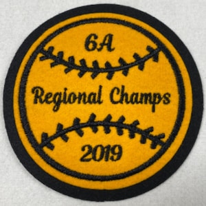 Pode incluir: Um remendo bordado preto e dourado com um design de beisebol. O remendo diz "6A Regional Champs 2019".