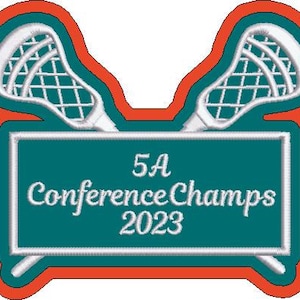 Puede incluir: Parche bordado con dos palos de lacrosse blancos sobre un rectángulo turquesa. El rectángulo muestra el texto "5A Conference Champs 2023" en escritura blanca, delineado en blanco. El parche tiene un borde naranja y rojo.