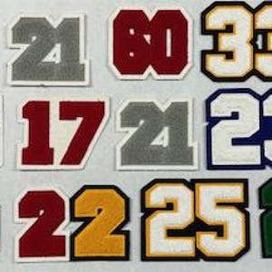 以下が含まれることがあります： さまざまな色でさまざまな数字が書かれたアイロン接着パッチのセットです。数字は3から106までです。
