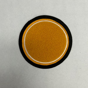 以下が含まれることがあります： 白と黒の縁取りのある丸い黄色のフェルトパッチ