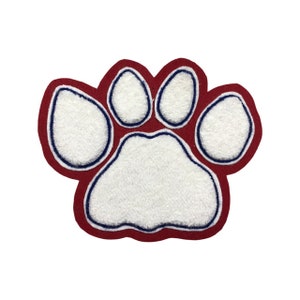 Op de afbeelding: Een grote, zachte pootafdrukpatch met een wit midden en een donkerrode rand. De witte pootafdruk is omrand met een dunne blauwe lijn. Deze patch is waarschijnlijk voor een jas of tas.