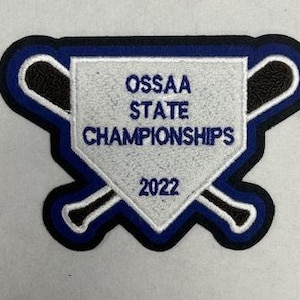 Könnte beinhalten: Ein weißer Filz-Patch mit blauem Rand und zwei braunen Baseballschlägern, die hinter einer weißen Homeplate gekreuzt sind. Die Homeplate trägt den Text "OSSAA STATE CHAMPIONSHIPS 2022" in Schwarz.