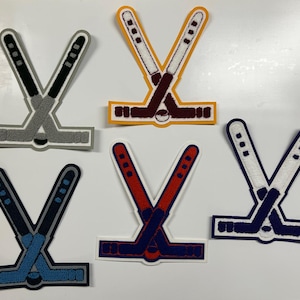 以下が含まれることがあります： さまざまな色の組み合わせの、刺繍されたホッケーのスティックパッチが5つ。パッチは、交差するホッケースティックと交差点にあるパックが特徴です。色はグレー、ブラウン、レッド、ブルー、ネイビーで、白と黒のアクセントが付いています。