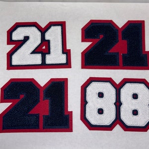 以下が含まれることがあります： 21と88の数字が書かれたアイロン接着パッチが4つ。パッチは赤、白、青。数字は太字のブロック体です。