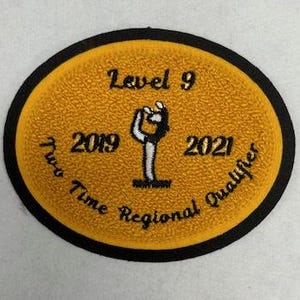 May include: A yellow and black embroidered patch with the text "Level 9 Two Time Regional Qualifier 2019 2021" and a stylized image of a person holding a child.