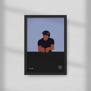 Puede incluir: Lámina artística enmarcada con una ilustración minimalista de un DJ. La obra representa a una persona con gorra y auriculares negros, apoyada en una superficie negra sobre un fondo azul claro. El texto "DJ EZ" está en la parte inferior.