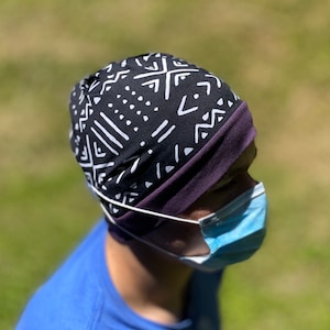 May include: A person wearing a black and white patterned beanie with a purple trim and a blue face mask.