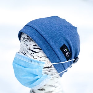 May include: A blue beanie with a button and elastic straps to hold a face mask in place. The beanie has a small black label with the word "brch" on it.