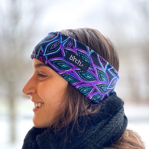 May include: A woman wearing a black headband with a colorful paisley pattern. The headband has the word "birch" printed on it.