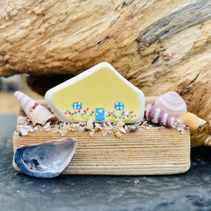 The cutest Sea Pottery and Sea Glass painted cottages on driftwood with shells.