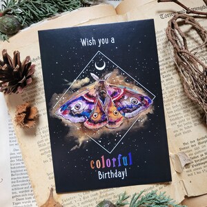 May include: A black card with a colorful butterfly illustration and the text "Wish you a colorful Birthday!" on a black background with a crescent moon and stars.