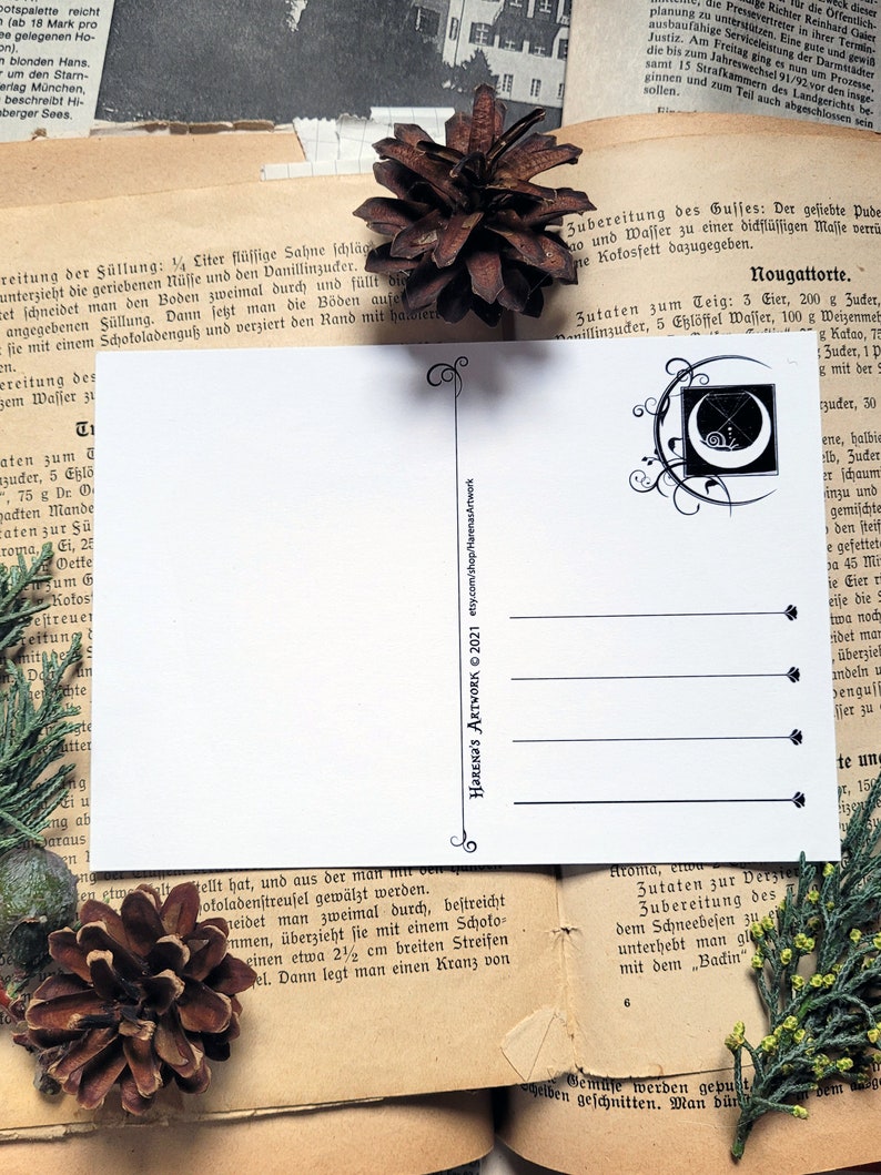 May include: A white postcard with a black and white illustration of a crescent moon with a cross inside. The illustration is surrounded by a decorative border. The text "HARENA'S ARTWORK &copy; 2021" is printed in black at the bottom right corner of the postcard.