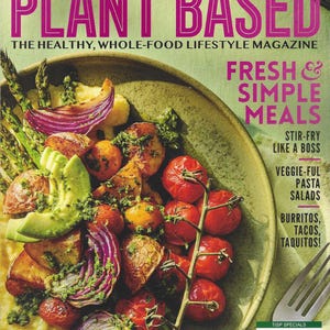 May include: The cover of "Forks Over Knives Plant Based" magazine features a vibrant plant-based meal. The dish includes roasted tomatoes, potatoes, red onion, avocado, and asparagus. The magazine promotes fresh, simple meals.