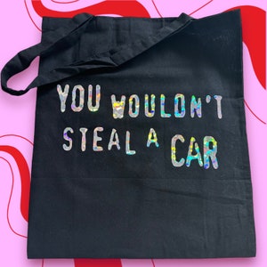 May include: Black tote bag with a silver iridescent graphic that reads "YOU WOULDN'T STEAL A CAR".