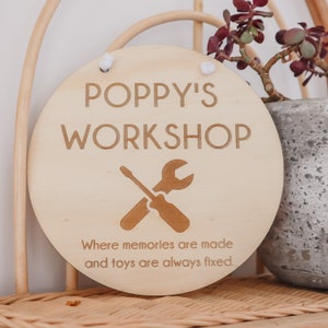 May include: A round wooden sign with the text "Poppy's Workshop" and a crossed screwdriver and wrench. The sign also says "Where memories are made and toys are always fixed."