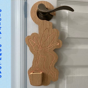 May include: Wooden door hanger with a fairy design and a small wooden bucket. The hanger is attached to a door with a doorknob.