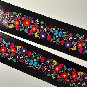 May include: Two black strips of fabric with a colorful floral pattern. The pattern features red, yellow, blue, green, and purple flowers and leaves.