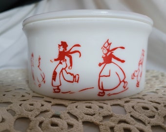 May include: White ceramic bowl with a lid, featuring a red and white design of people ice skating. The bowl has a rounded shape and a smooth, glossy finish.