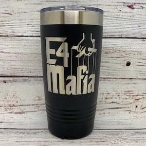 May include: Black stainless steel tumbler with a silver inscription that reads "E4 Mafia" with a hand holding strings above the text.