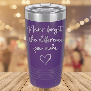 May include: Purple stainless steel tumbler with a silver lid and the text "Never forget the difference you make" with a heart symbol.