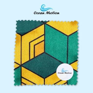 Puede incluir: Una muestra de tela cuadrada con un patrón geométrico en tonos amarillos y verdes, delineado en negro. La tela tiene una apariencia texturizada. El logotipo de Ocean Motion es visible.