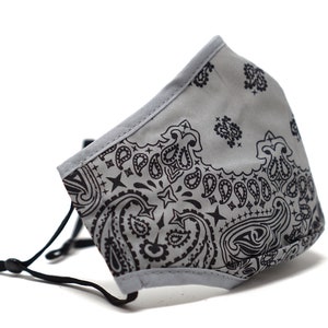 May include: A gray face mask with a black paisley pattern. The mask has elastic ear loops.
