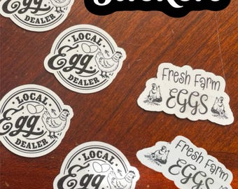 May include: A collection of white stickers with black text and illustrations. The stickers feature the words "Local Egg Dealer" and "Fresh Farm Eggs", along with images of chickens and eggs. The word "Stickers" is also present.