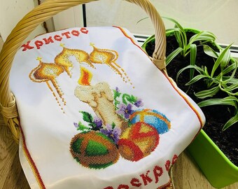 May include: White embroidered cloth featuring a candle, three Easter eggs, and the Cyrillic text "ХРИСТОС ВОСКРЕС". The cloth is adorned with a gold trim and lace.