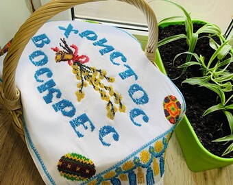 May include: White embroidered fabric with the text "Христос Воскресе" in blue and yellow thread. The fabric features a depiction of a willow branch with yellow and blue beads, and two colourful Easter eggs.