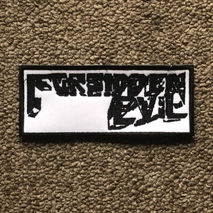Op de afbeelding: Zwart-witte geborduurde patch met de tekst "Forbidden Evil" in een vet, gestileerd lettertype.