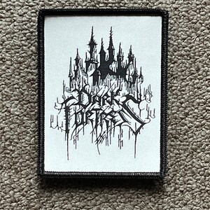 May include: Black and white embroidered patch with the text "Dark Fortress" and a black castle design.