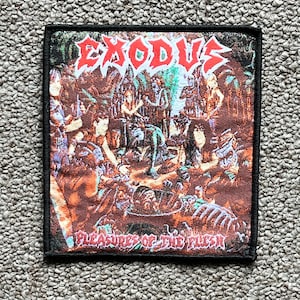 May include: A woven patch with a black border featuring the band Exodus. The patch has a red and orange background with a graphic of a skull and bones. The text "Pleasures of the Flesh" is printed in white at the bottom of the patch.