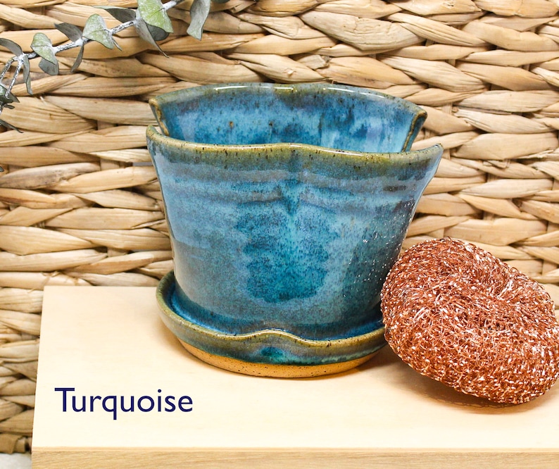 May include: Turquoise ceramic planter with a wavy rim and a light brown base. The planter is sitting on a wooden surface with the word "Turquoise" written in blue.