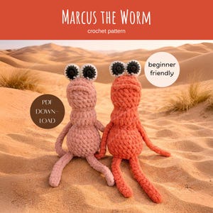 Könnte beinhalten: Zwei gehäkelte Wurmspielzeuge, eines rosa und eines orangefarben, mit großen schwarz-weißen Augen. Die Spielzeuge sitzen auf Sand, mit dem Text "Marcus the Worm" und "crochet pattern" darüber. Ein Kreis liest "beginner friendly".