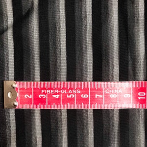 May include: A red measuring tape with white markings and the words "FIBER-GLASS" and "CHINA" printed on it. The tape is marked with numbers from 2 to 10.