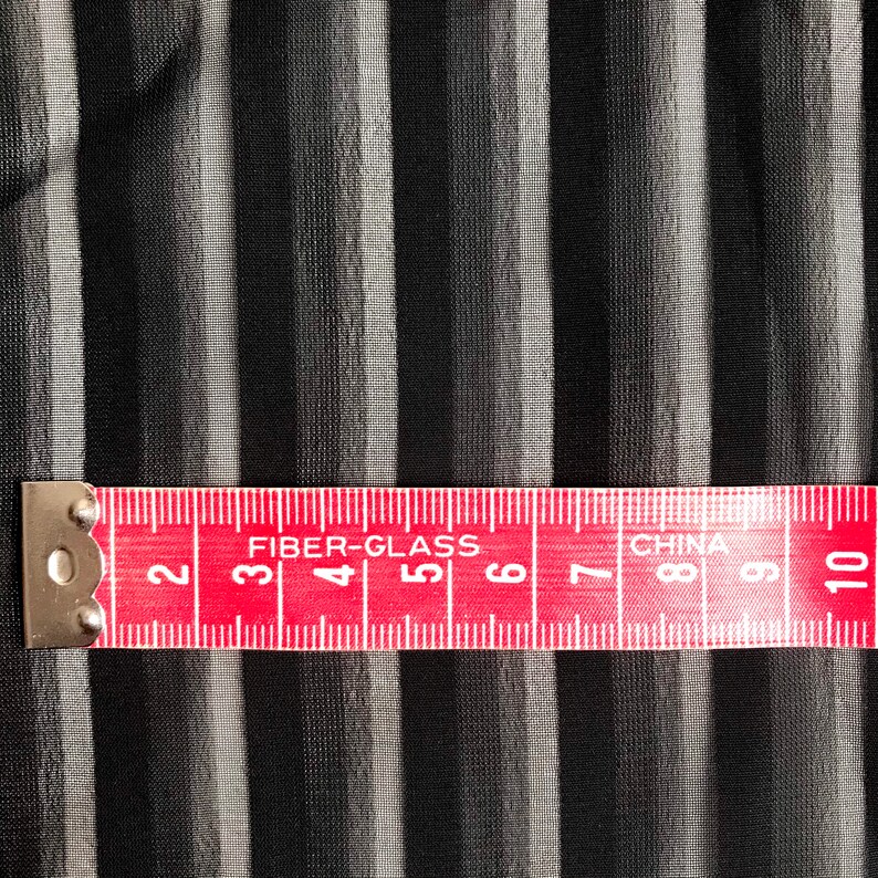 May include: A red measuring tape with white markings and the words "FIBER-GLASS" and "CHINA" printed on it. The tape is marked with numbers from 2 to 10.