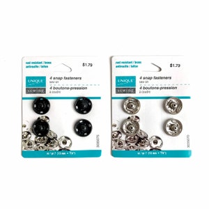 May include: Two packs of black and silver snap fasteners for sewing. Each pack contains four snap fasteners and is labelled "UNIQUE sewing 4 snap fasteners sew on 4 boutons-pression à coudre" and "sz/gr 7 (15 mm - 5/8")".