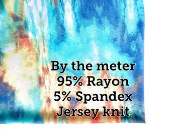 Puede incluir: Primer plano de una tela de teñido anudado azul, naranja y blanca con el texto "By the meter 95% Rayon 5% Spandex Jersey knit".